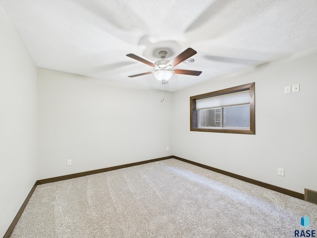 carpeted spare room with a ceiling fan, baseboards, and a textured ceiling