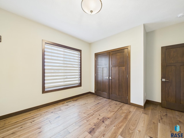 unfurnished bedroom featuring visible vents, baseboards, light wood-style floors, and a closet