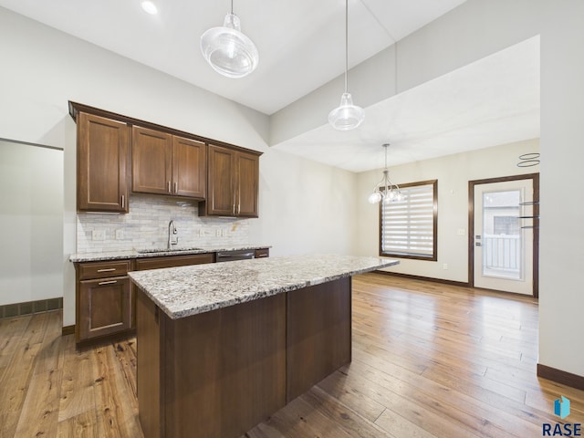 kitchen with light wood-type flooring, baseboards, a sink, and tasteful backsplash
