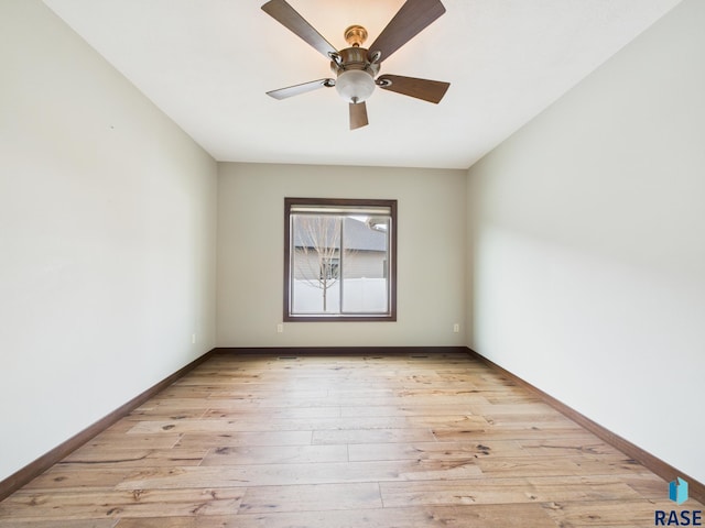 empty room with light wood-type flooring, a ceiling fan, and baseboards