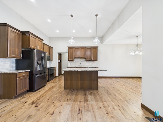 kitchen with tasteful backsplash, light stone countertops, light wood finished floors, and stainless steel appliances