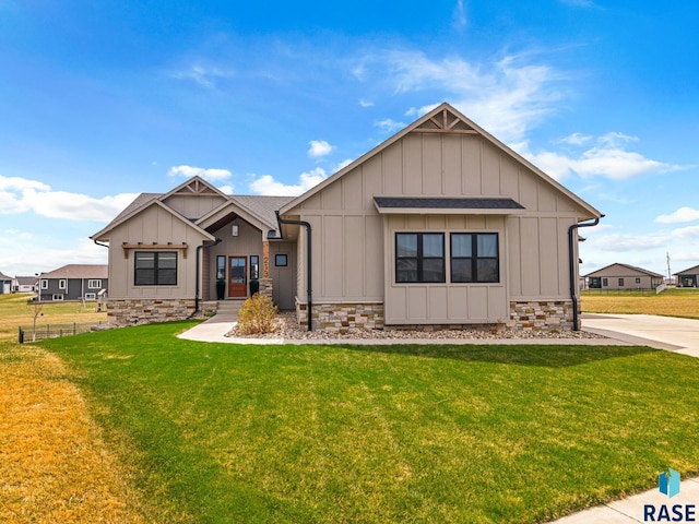 view of front facade with a front lawn, fence, stone siding, and board and batten siding