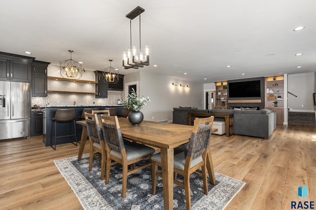 dining area featuring stairs, light wood-style floors, baseboards, a notable chandelier, and recessed lighting
