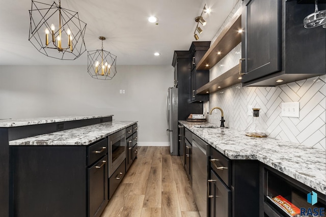 kitchen featuring a center island, a sink, dark cabinetry, decorative backsplash, and appliances with stainless steel finishes