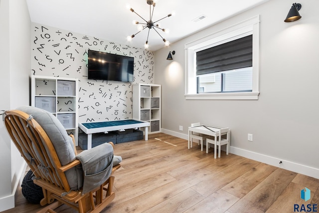 living area featuring wood finished floors, visible vents, baseboards, and an inviting chandelier