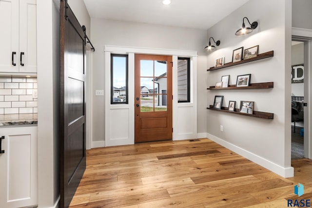 doorway featuring a barn door, light wood-style floors, baseboards, and recessed lighting