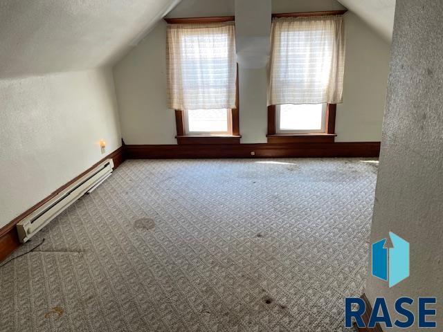 1131 Williams St, Larchwood, IA 51241 - bonus room featuring a baseboard heating unit, vaulted ceiling, baseboards, and carpet