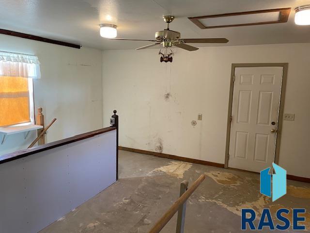 1131 Williams St, Larchwood, IA 51241 - spare room featuring unfinished concrete floors, baseboards, and ceiling fan