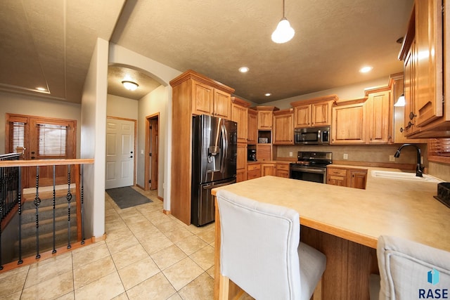 7304 W Lobelia St, Sioux Falls, SD 57106 - kitchen with appliances with stainless steel finishes, a sink, light countertops, arched walkways, and a peninsula