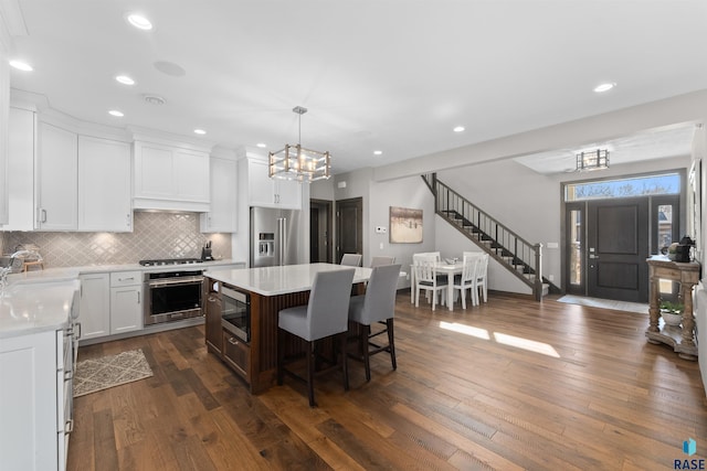 912 Torrey Pine Ln, Sioux Falls, SD 57110 - kitchen with stainless steel appliances, light countertops, a kitchen bar, backsplash, and a notable chandelier