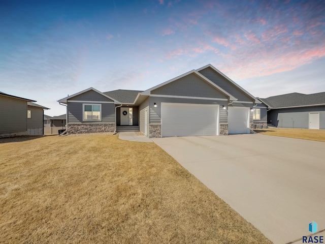 craftsman inspired home with stone siding, driveway, a yard, and a garage
