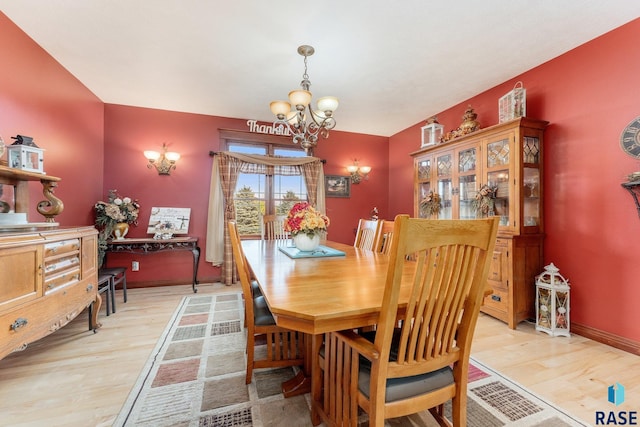 dining area featuring light wood-style flooring, baseboards, and a notable chandelier