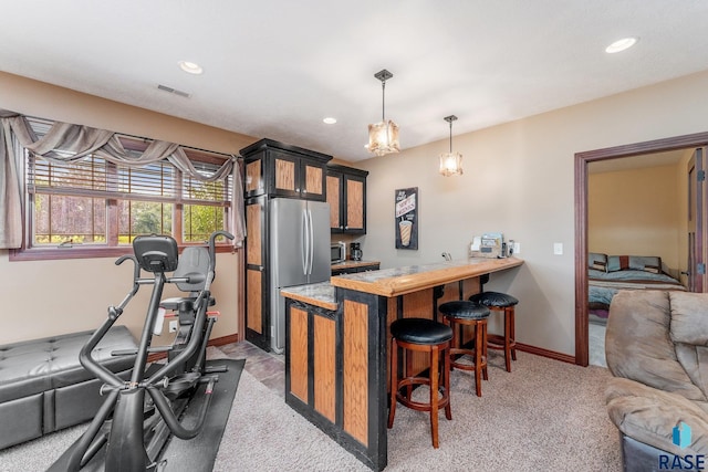 kitchen with stainless steel appliances, visible vents, a peninsula, glass insert cabinets, and a breakfast bar area