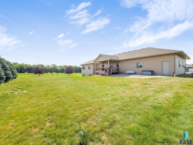 rear view of property featuring a lawn and a wooden deck