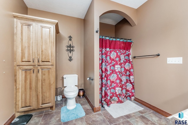 bathroom featuring baseboards, a shower with shower curtain, and toilet