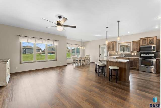 3508 E Prairie Wind St, Sioux Falls, SD 57108 - kitchen with stainless steel appliances, a center island, a kitchen bar, decorative backsplash, and a ceiling fan