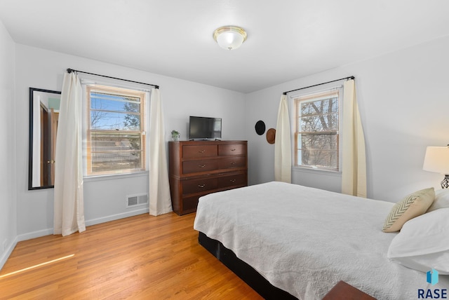 bedroom with baseboards, visible vents, and light wood-style flooring