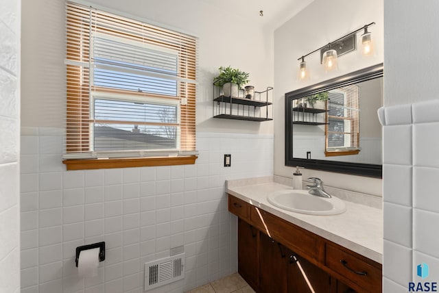 bathroom featuring tile walls, visible vents, vanity, and a wealth of natural light