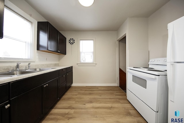1330 W 14th St, Sioux Falls, SD 57104 - kitchen with a healthy amount of sunlight, a sink, white appliances, and dark cabinetry