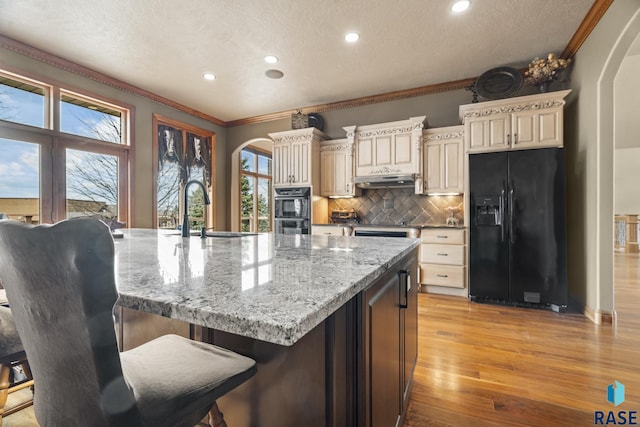 6301 S Grand Prairie Dr, Sioux Falls, SD 57108 - kitchen with cream cabinets, black appliances, arched walkways, and a sink