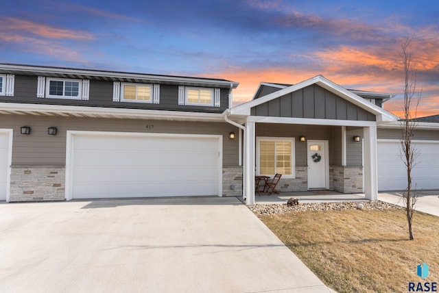 view of front facade with board and batten siding, a porch, stone siding, and concrete driveway