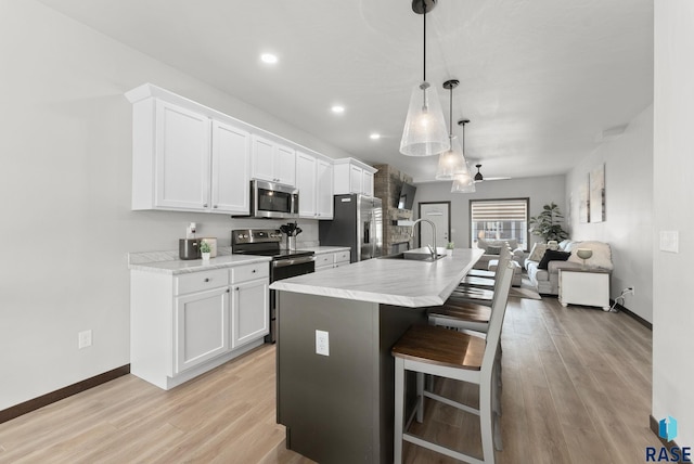 kitchen with white cabinets, appliances with stainless steel finishes, a sink, and a breakfast bar
