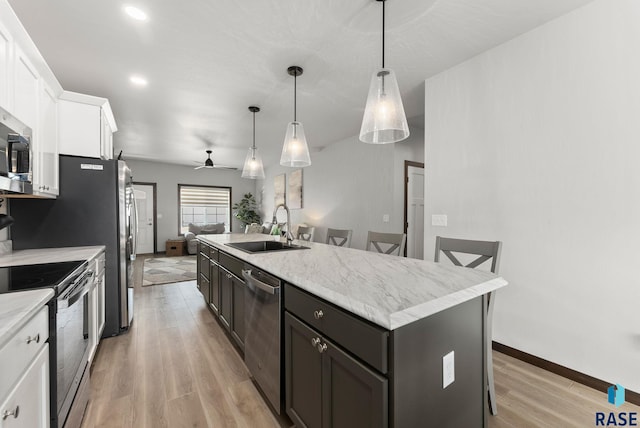 kitchen with white cabinets, stainless steel appliances, a ceiling fan, a sink, and light wood-style floors