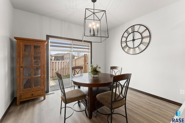dining space featuring baseboards, an inviting chandelier, and light wood-style flooring