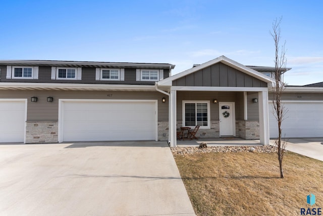view of front facade featuring a garage, a porch, stone siding, and driveway