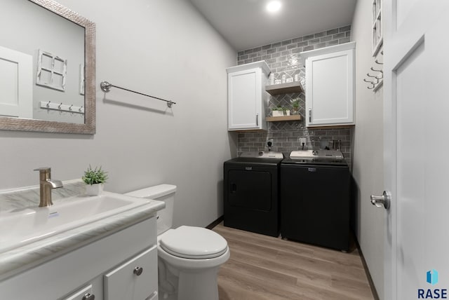 bathroom featuring wood finished floors, washer and clothes dryer, vanity, backsplash, and toilet