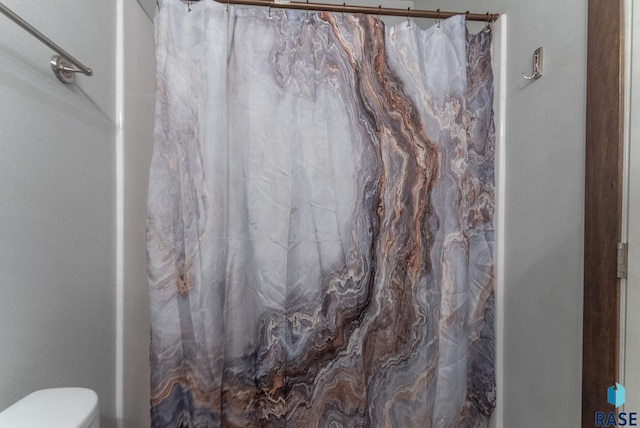 bathroom featuring toilet and a shower with curtain