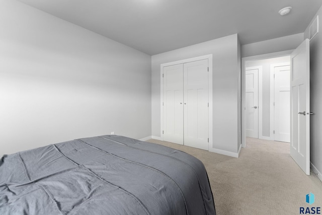 carpeted bedroom with baseboards and a closet