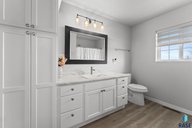 full bath with toilet, baseboards, visible vents, wood finished floors, and vanity