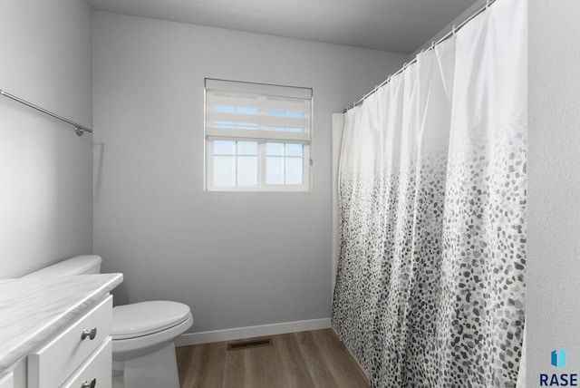 full bath with wood finished floors, visible vents, toilet, vanity, and baseboards