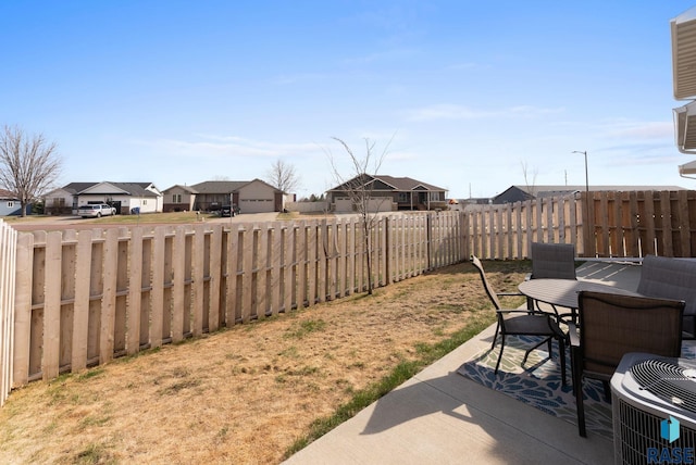 view of yard with a fenced backyard, outdoor dining space, central air condition unit, a residential view, and a patio area