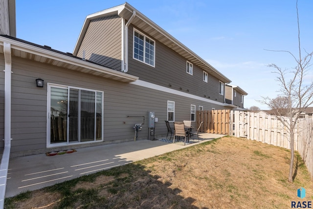 rear view of house with fence, a patio area, and a yard
