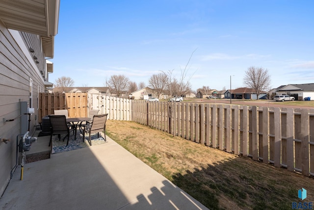 view of yard featuring a residential view, a fenced backyard, a patio, and outdoor dining area
