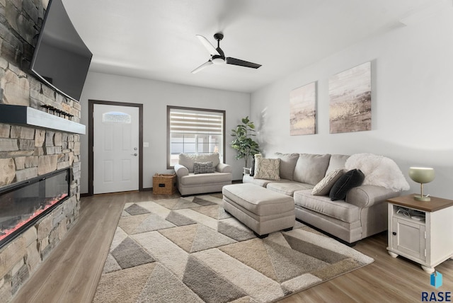 living area with ceiling fan, light wood finished floors, and a fireplace