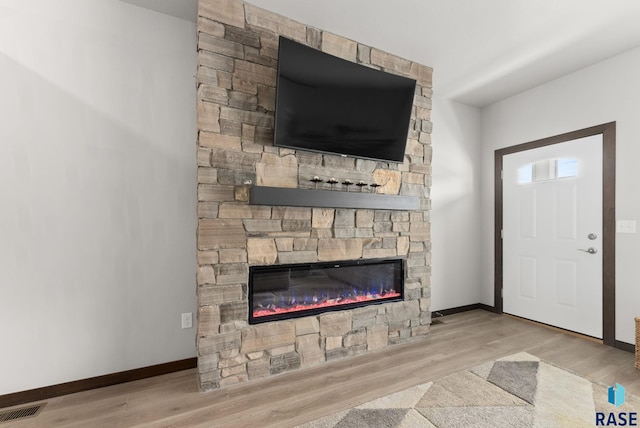 unfurnished living room with baseboards, wood finished floors, visible vents, and a fireplace