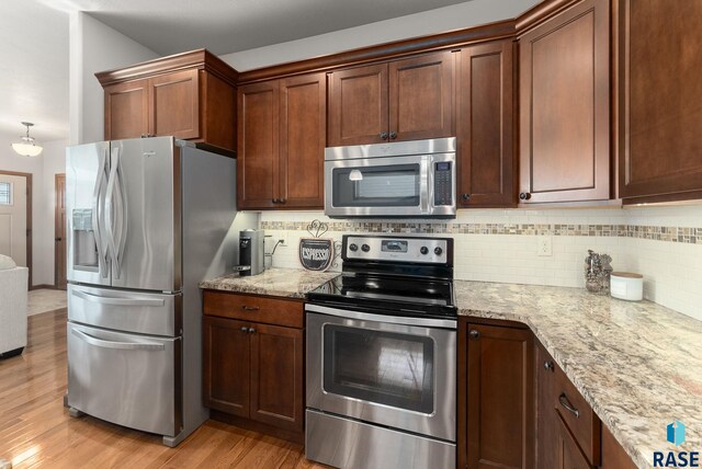 5508 S Sirocco Ave, Sioux Falls, SD 57108 - kitchen with backsplash, light wood-style floors, light stone countertops, and appliances with stainless steel finishes