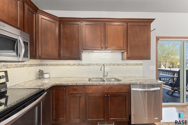 5508 S Sirocco Ave, Sioux Falls, SD 57108 - kitchen featuring light stone counters, a sink, appliances with stainless steel finishes, and tasteful backsplash