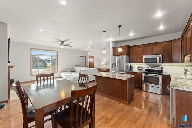 5508 S Sirocco Ave, Sioux Falls, SD 57108 - kitchen with a center island, a sink, decorative backsplash, light wood finished floors, and appliances with stainless steel finishes
