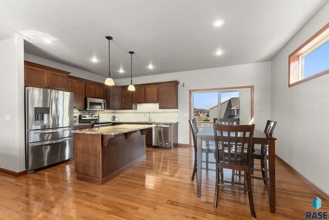 5508 S Sirocco Ave, Sioux Falls, SD 57108 - kitchen with light wood finished floors, tasteful backsplash, appliances with stainless steel finishes, and a center island