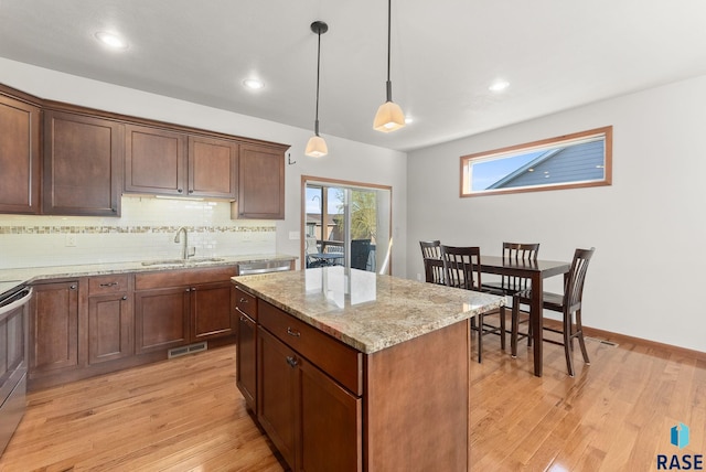5508 S Sirocco Ave, Sioux Falls, SD 57108 - kitchen with a center island, tasteful backsplash, a sink, light wood-type flooring, and light stone countertops