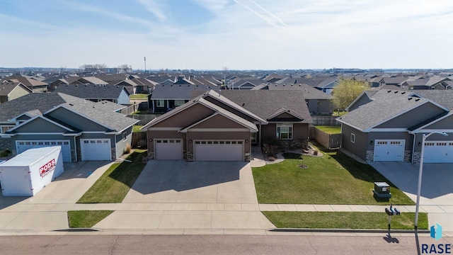 5508 S Sirocco Ave, Sioux Falls, SD 57108 - view of front facade with concrete driveway, a front lawn, stone siding, a garage, and a residential view