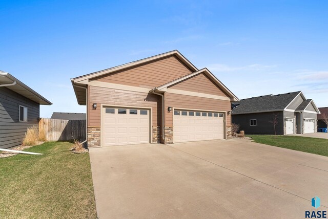5508 S Sirocco Ave, Sioux Falls, SD 57108 - view of front of house with stone siding, concrete driveway, fence, a garage, and a front yard