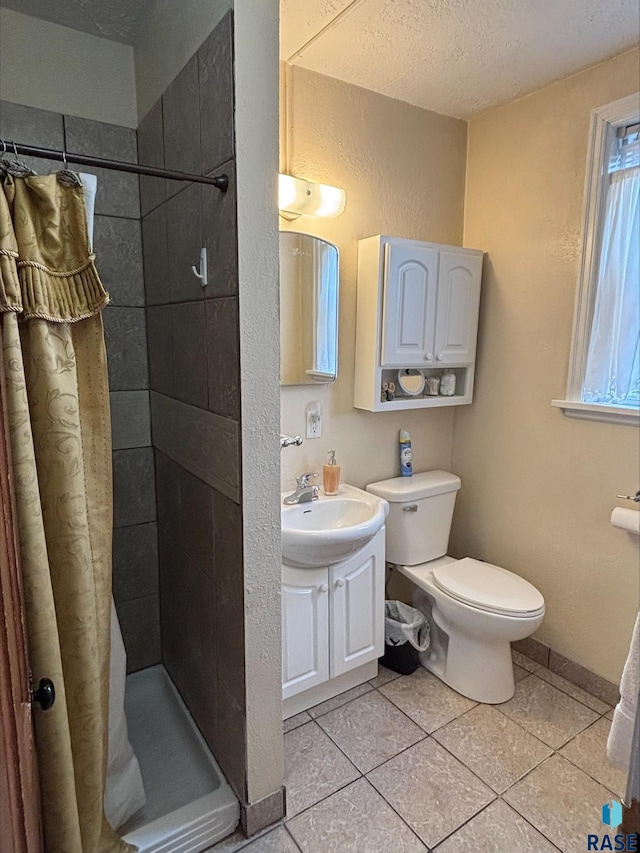 full bathroom featuring a textured ceiling, a stall shower, toilet, vanity, and tile patterned flooring