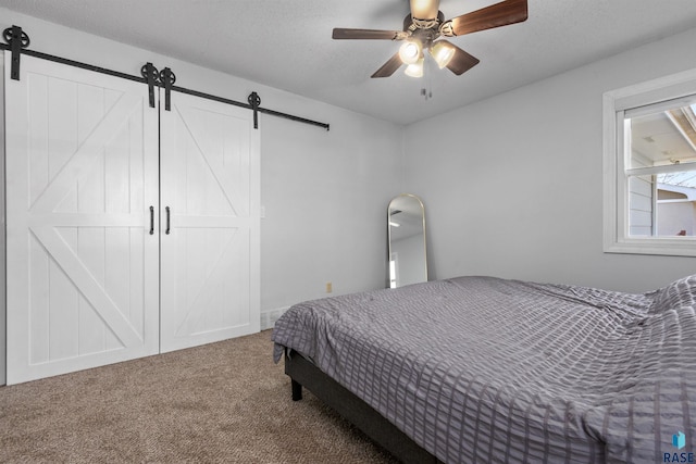 carpeted bedroom featuring a barn door and a ceiling fan