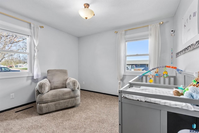 bedroom featuring visible vents, a crib, baseboards, and carpet floors