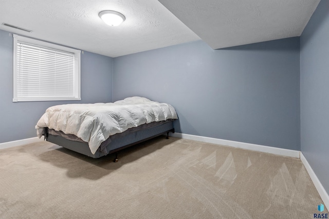 bedroom with a textured ceiling, carpet floors, visible vents, and baseboards